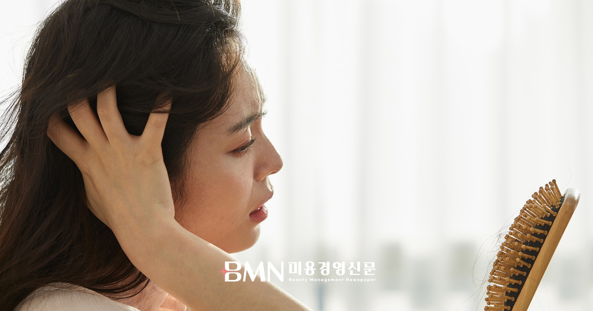 탈모를 걱정하며 머리카락 상태를 확인하는 여성