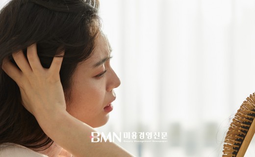 탈모를 걱정하며 머리카락 상태를 확인하는 여성