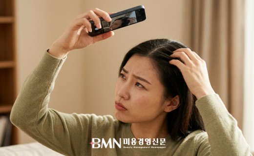 스마트폰으로 자신의 정수리 가르마를 확인하는 여성